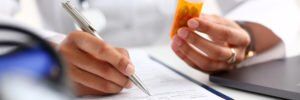 Atripla Lawsuit for Bone Loss and Kidney Damage doctor holding prescription bottle and writing a prescription